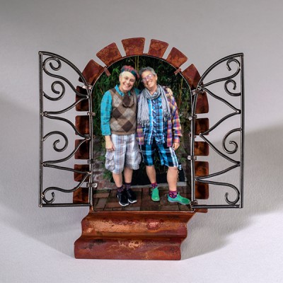 metal art photo frame with copper 'stairs' and copper surrounding an open door shape with the copper in the shape of masonry bricks. Silver forms two open gate doors in the style of wrought iron.A color photo is inside.