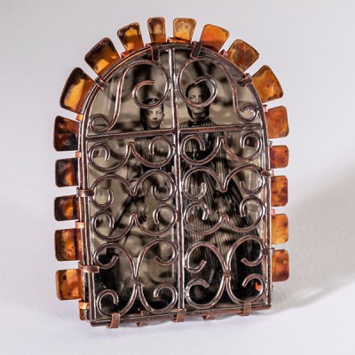 Brooch with copper rays, silver gates in the shape of wrought iron, with a black and white photo behind them